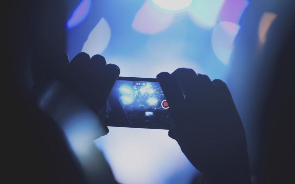 Spectator filming concert with his cell phone.